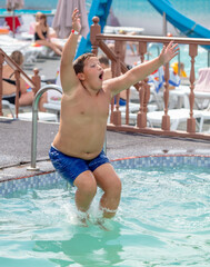 The boy jumps into the pool with a run.