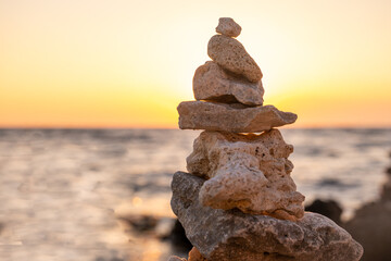 Fototapeta na wymiar Stones stacked in a turret in the rays of the setting sun. Marine weathered limestone