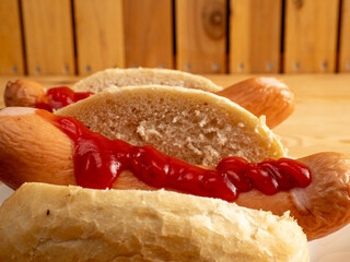 Boiled sausage with a bun on a wooden background.
