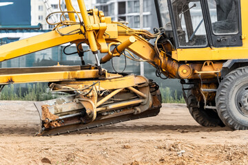 Road grader at the construction site. Powerful construction machine for ground leveling and excavation. Close-up. Professional construction equipment.