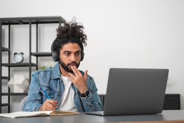 Businessman wearing casual wear is listening to podcast taking notes