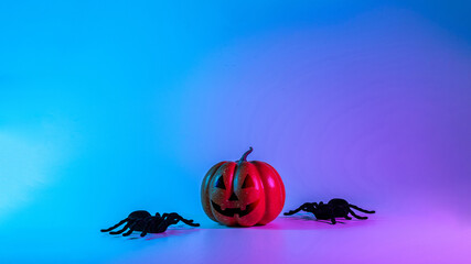 Halloween banner. Scary spooky pumpkin, black night spider on night neon helloween background. Minimalistic background for autumn holidays. Space for text.
