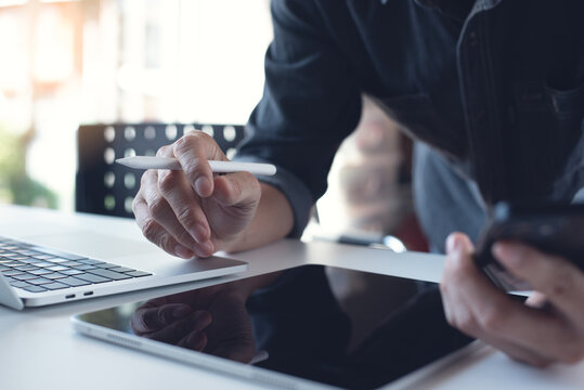 Business man working remotely on laptop computer, using digital tablet and mobile phone at home, closeup