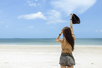 woman wearing black bowler on her head and wear a back short pants stand on the beach on sunny day