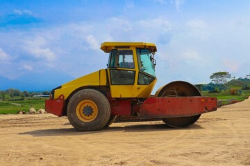 road roller with yellow color, on construction site and sky background