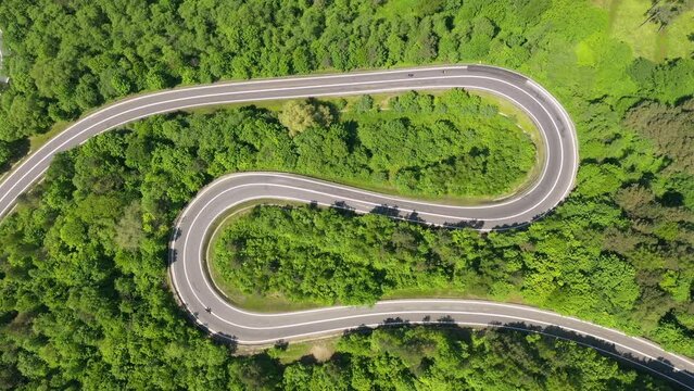 Aerial drone view of winding road between green fields	
