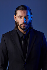 Fototapeta premium Studio portrait of bearded man wearing suit on blue background.