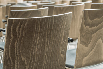 frei schwingende leere Stühle mit Maserung aus Holz stehen nebeneinander in Reihen - Ansicht der...