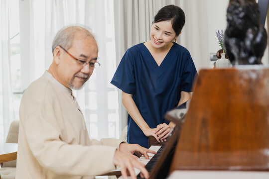 Asian nurse, doctor woman assisting take care and be pleased with Senior Asian patient man playing piano to relax the mind.