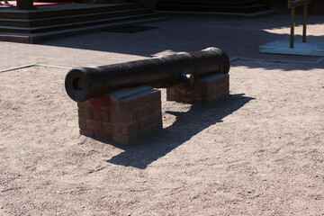 The barrel of an artillery gun standing on two brick pedestals