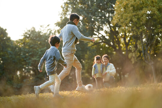 young asian family with two children enjoying outdoor sport in park