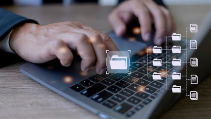 Document Management System (DMS) being setup by IT consultant working on laptop computer in office. Software for archiving, searching and managing corporate files and information