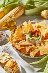 corn nachos with guacamole on a light background in the rays of the sun