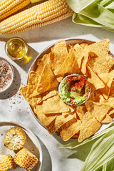 corn nachos with guacamole on a light background in the rays of the sun