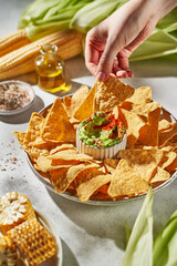 corn nachos with guacamole on a light background in the rays of the sun