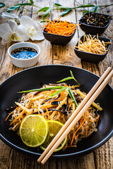 Asian food - konjac noodles, stir fried vegetables, soy sauce and mushrooms on wooden table

