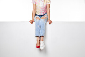 female legs in jeans and white sneakers sitting