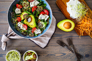 Fresh salad - manouri cheese, avocado, grapes and green vegetables on wooden table
