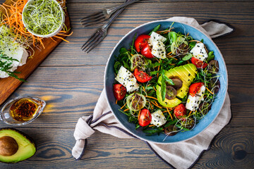 Fresh salad - manouri cheese, avocado, grapes and green vegetables on wooden table
