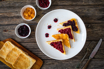Toasted bread with fruit jam on wooden background
