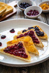 Toasted bread with fruit jam on wooden background
