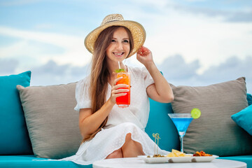 Woman holding mai tai cocktail at outdoors bar or restaurant