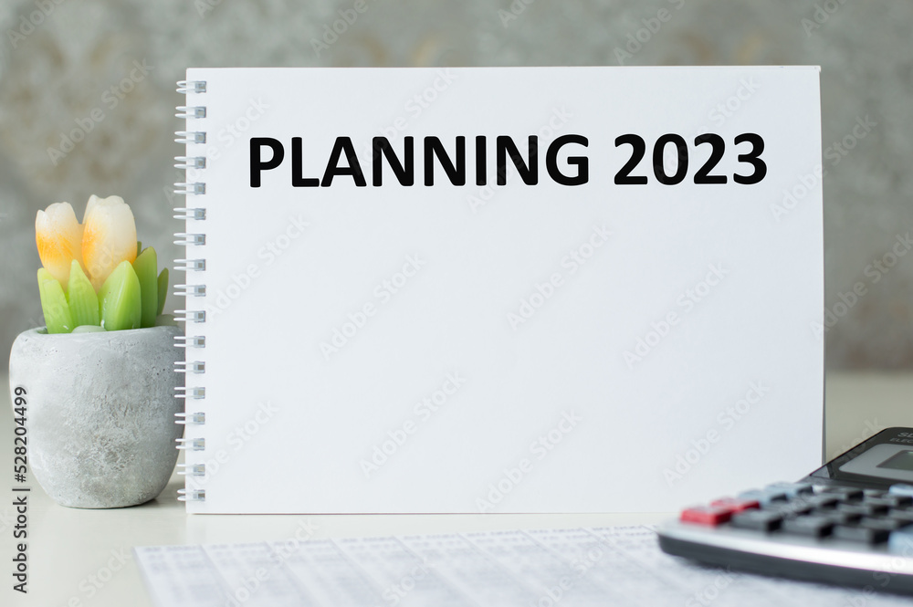 Aufkleber planning 2023 text on a notepad on the table next to a calculator and a flower in a pot. business, g