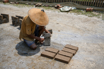 Kudus, Indonesia - September, 2022 : A male worker is making red bricks (batu bata merah) using a...