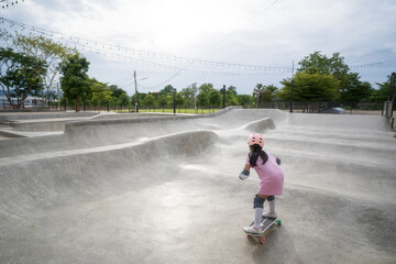 asian child skater or kid girl playing skateboard or ride surf skate and fun in pump track or wave...
