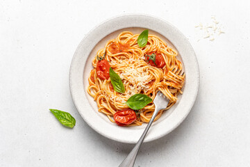 Spaghetti pasta with tomatoes and basil in ceramic plate on white background. Traditional Italian pasta with tomato sauce. Mediterranean cuisine