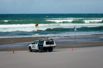 lifeguard truck parking in front of the ocean between swimming flags gold coast