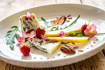 Fresh salad - blue cheese, raspberries, pear, arugula and pecan nuts on wooden background

