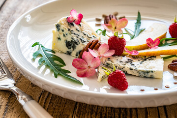 Fresh salad - blue cheese, raspberries, pear, arugula and pecan nuts on wooden background
