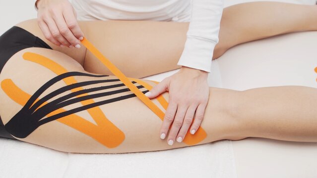 Therapist is applying tape to female body. Physiotherapy, kinesiology and recovery treatment.