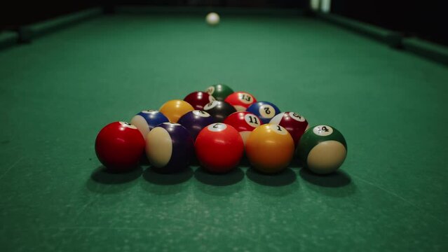 Billiard balls triangle starting position shot before the break. Pool balls with numbers organized in form of pyramid on a green cloth table. white cue ball seen in a distance