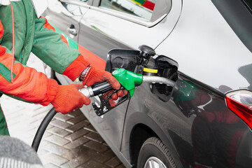 process of refueling car by employee in red jacket....