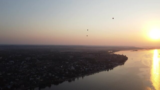ultra hd video footage 4k Aerial drone view of Balloons fly over the Volga River in Russia. Expanse of the riverside of the Volga near the city of Kostroma at summer  sunset