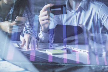 Fototapeta premium Double exposure of man and woman on-line shopping holding a credit card and forex graph hologram drawing. Stock market E-commerce pay on-line concept.
