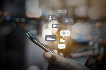 Person using a social media marketing concept on mobile phone with notification icons of like, message, comment and star above smartphone screen.