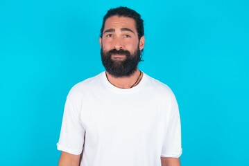 young bearded man wearing white T-shirt over blue studio background Pointing down with fingers showing advertisement, surprised face and open mouth