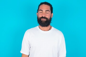 young bearded man wearing white T-shirt over blue studio background nice-looking sweet charming cute attractive lovely winsome sweet peaceful closed eyes