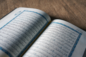 Fototapeta premium Indonesia - July, 2022 : The Quran, also romanized Qur'an or Koran, is central religious text of Islam, believed by Muslims to revelation from God (Allah). Classical Arabic. Sack, Blue. white. Open.