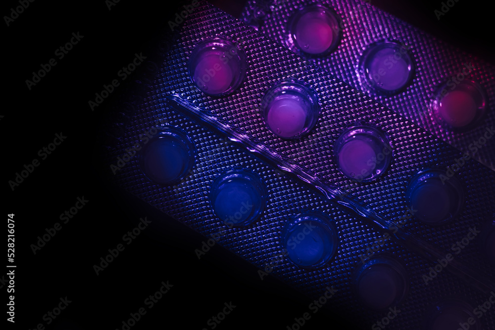 Aufkleber pills or drugs in a package under neon light on a dark background pattern for design..