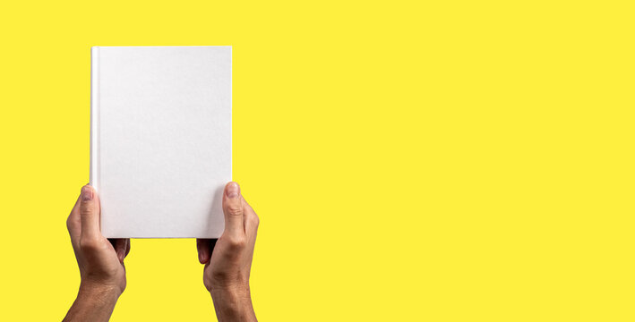 Banner with hands holding closed book mockup on yellow background. Novel, encyclopedia, cookbook, guide template with empty white cover. Education, literature concept. Copy space