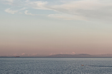 two ships at sea with mountains in background