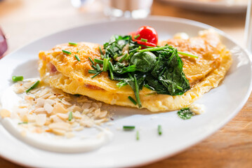 breakfast scrambled eggs with vegetables and spinach on a plate in a restaurant