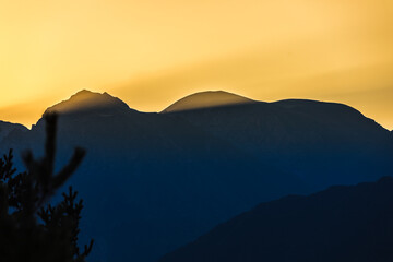 Sunrise in the mountains. Black silhouettes of mountain peaks