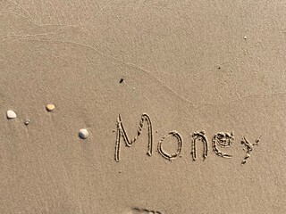Fototapeta na wymiar on the beach is carved with letters in the smooth sand the writing Money