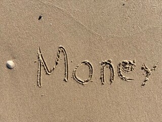 Fototapeta premium on the beach is carved with letters in the smooth sand the writing Money