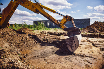 Excavator working at house construction site - digging foundations for modern house. Beginning of...